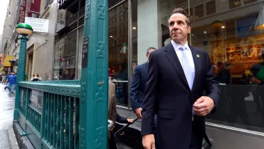 Former New York Governor Andrew Cuomo walking down city street.